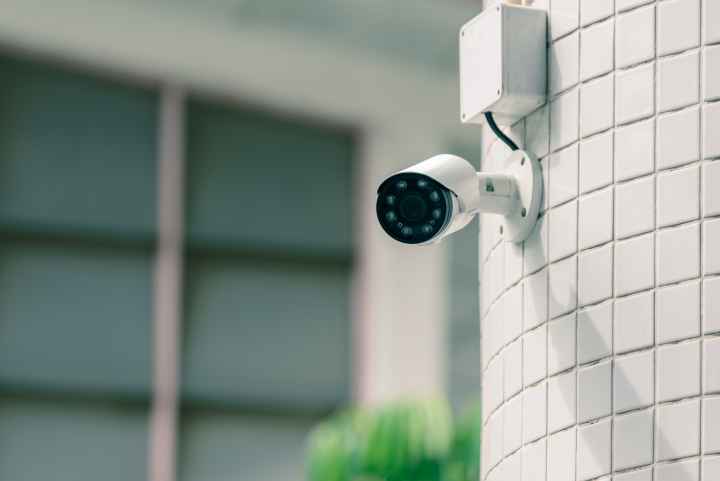 A photo of a camera mounted to a wall outside.