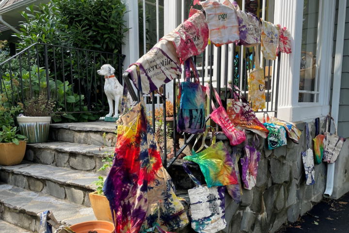 tie dye bags hanging over a railing in front of a white house 