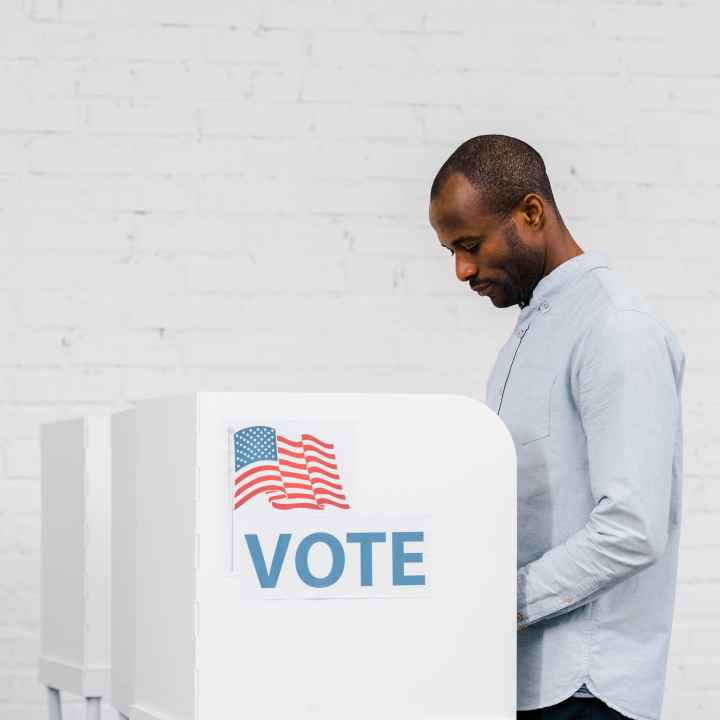 Black Man voting against a white brick background