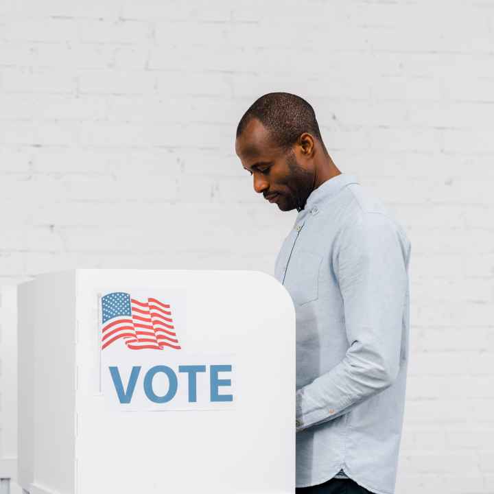 Black Man voting on white brick background