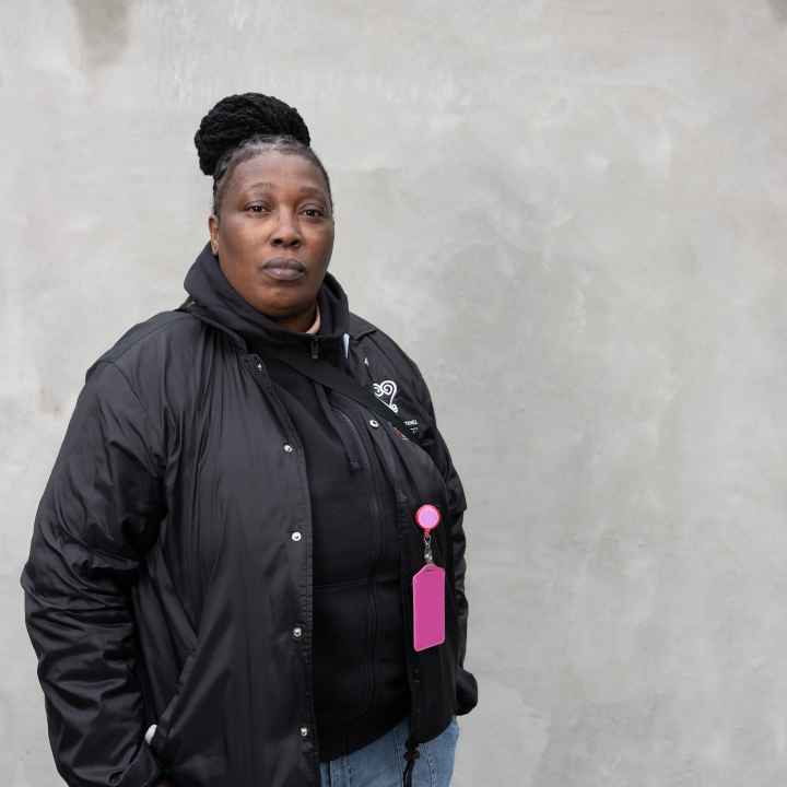 Black women wearing a black jacket in front of a grey background