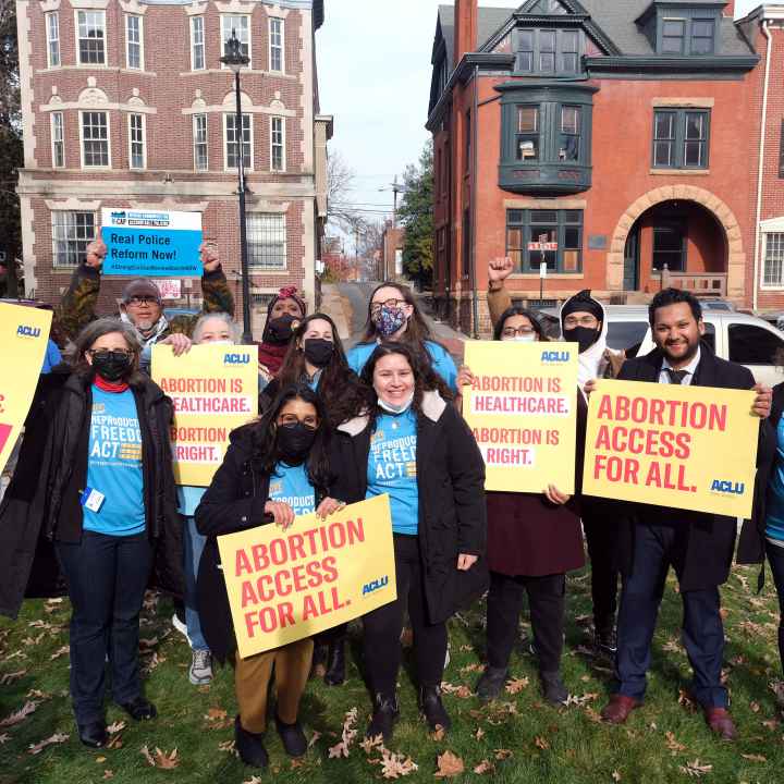 A group of people are standing with signs that read "abortion access for all" and "real police reform now"