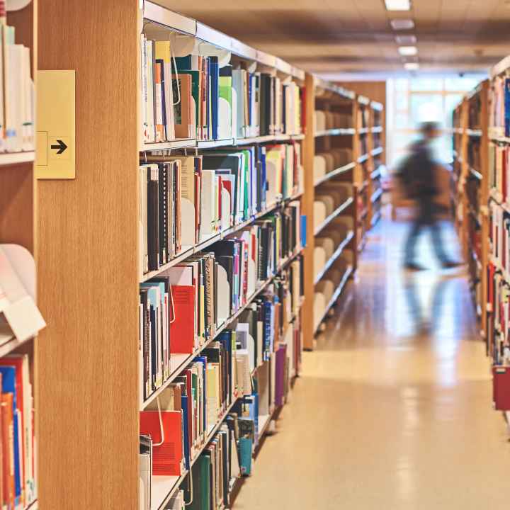 School library shelves with a blurred image of a person walking