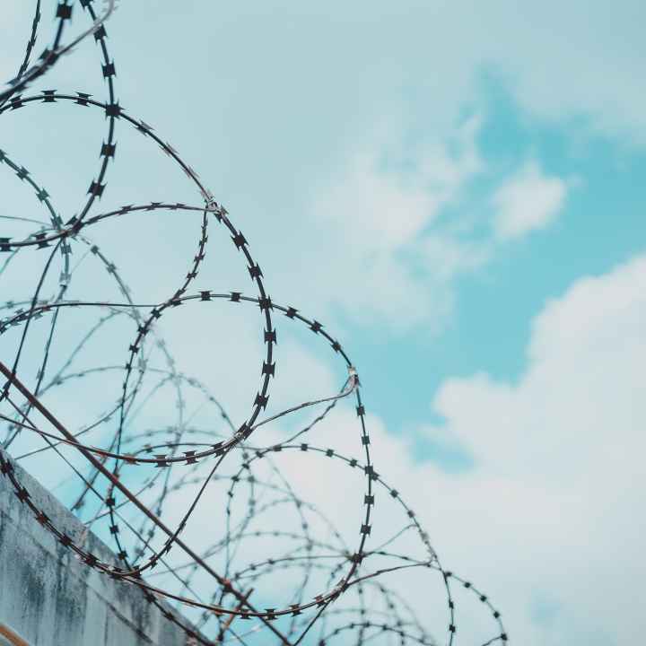 Barbed wire with blue sky and clouds in background