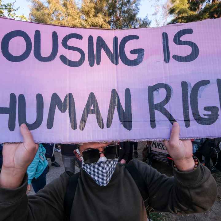 Man hold sign that reads "HOUSING IS A HUMAN RIGHT"