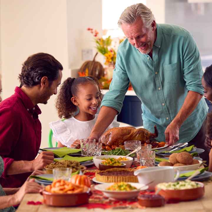 Mult-racial family enjoying thanksgiving dinner around a table