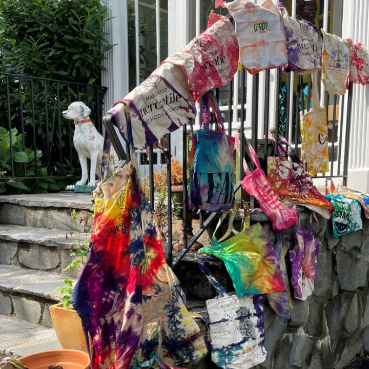 tie dye bags hanging over a railing in front of a white house 